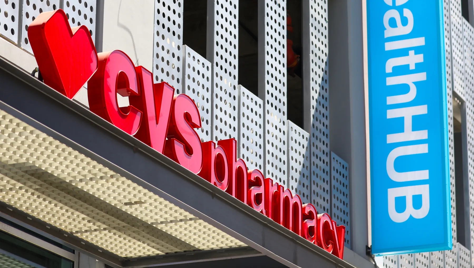 A view from below of the CVS sign on the center of a building, with a vertical blue HealthHub sign to its right.