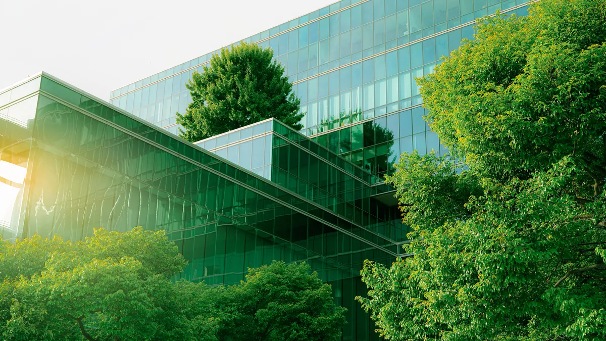 A facade of a sustainable glass office building with a tree for reducing carbon dioxide.