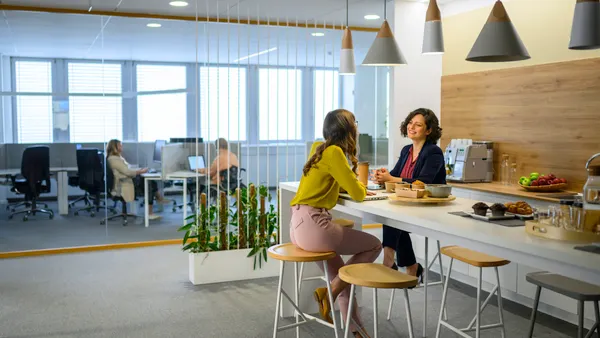 Businesswomen talking in office while taking break and eating lunch food.