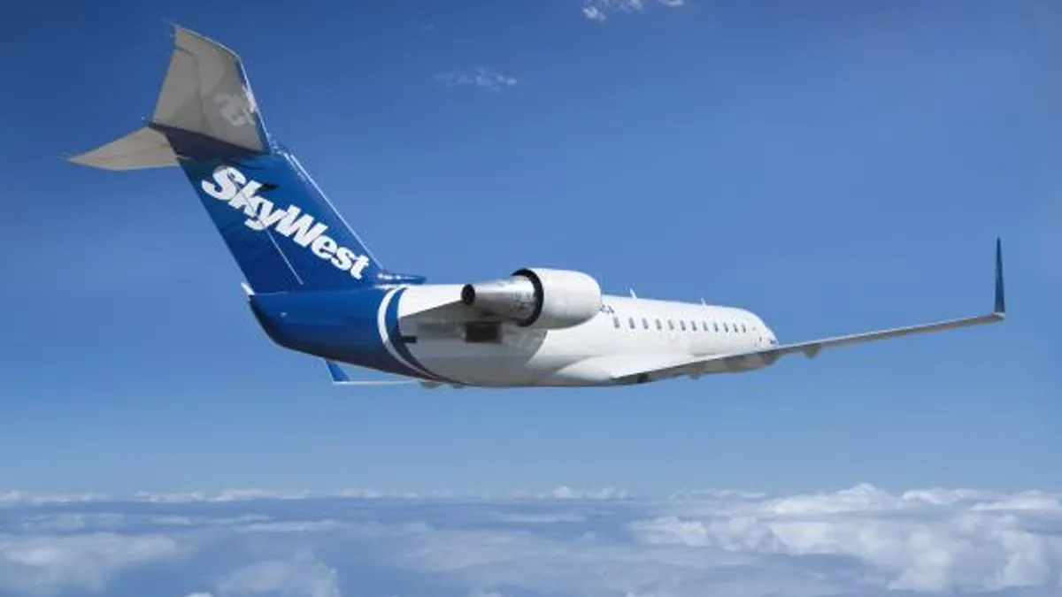 A small airplane is seen in the sky with SkyWest written on the tail.