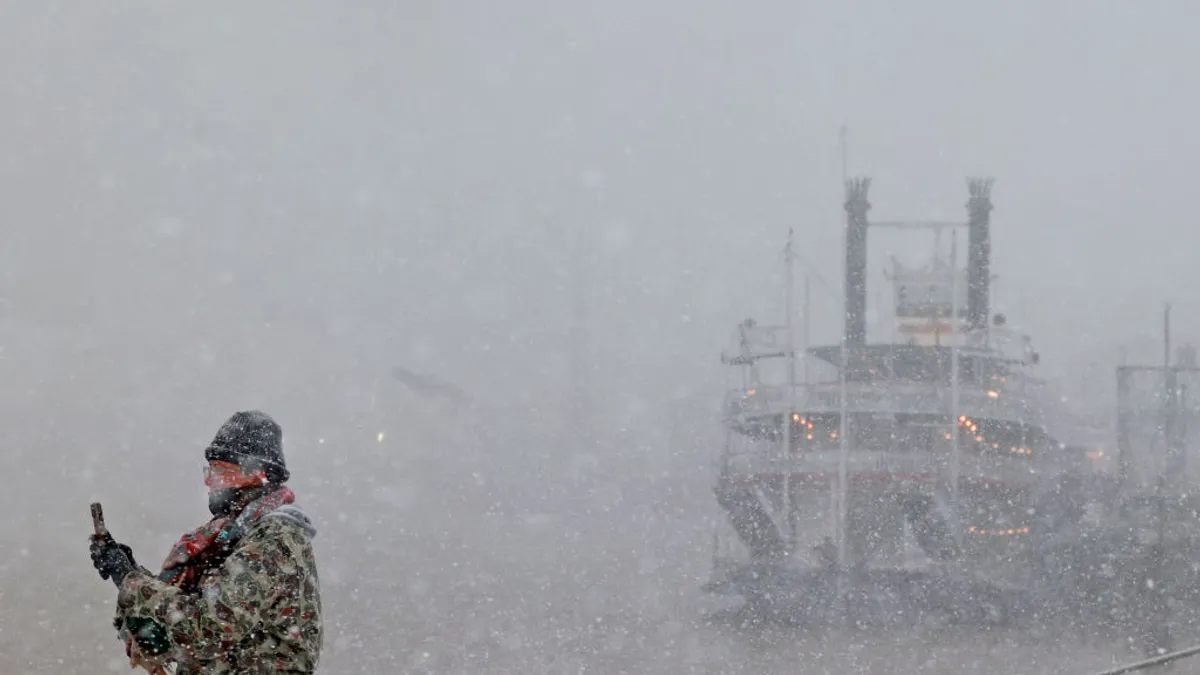 A man takes a picutre of a boat during a snowstorm