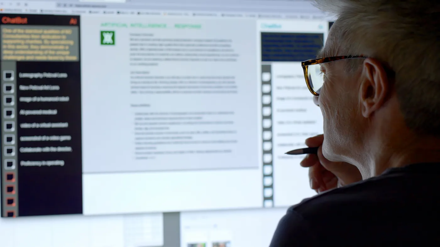 A man looks into a large computer screen displaying an artificial intelligence chatbot application.