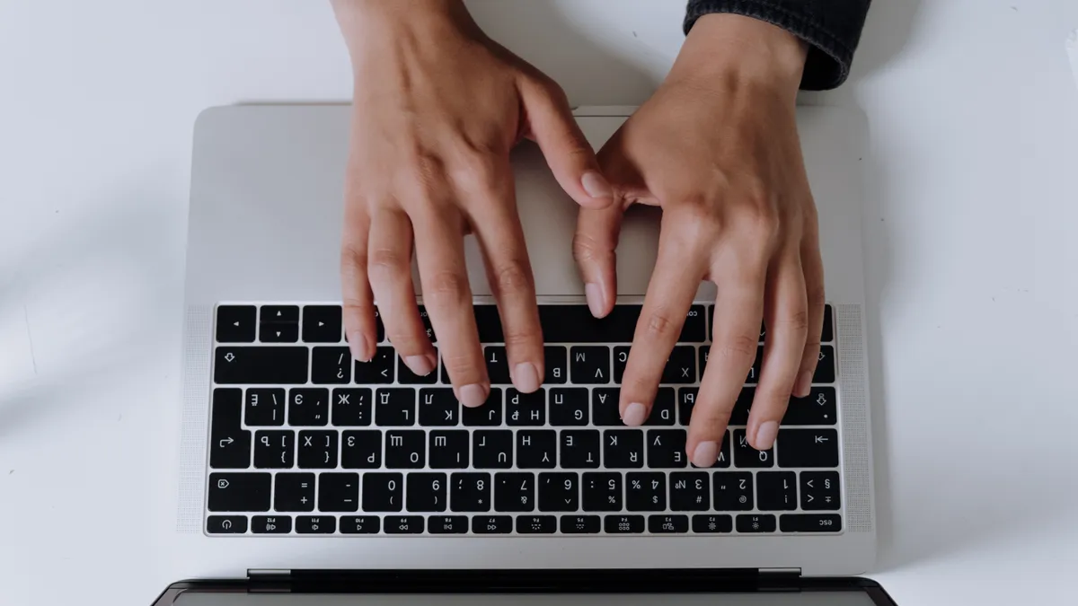 Brown hands type on a keyboard