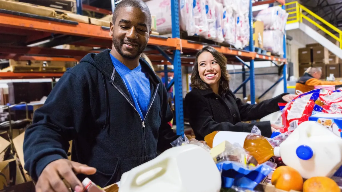 A woman and a man sorting boxes in assembly line at food bank