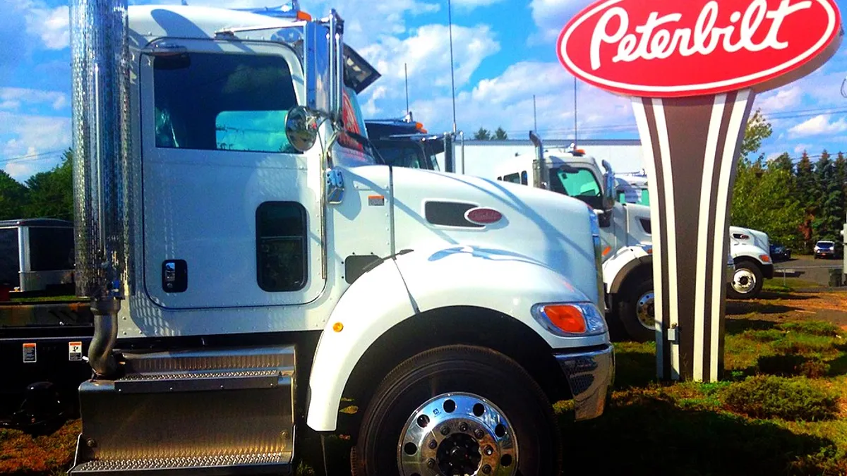 A Peterbilt truck in front of a Peterbilt sign.