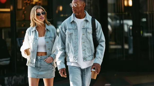 Two people cross the street in denim jackets and bottoms.