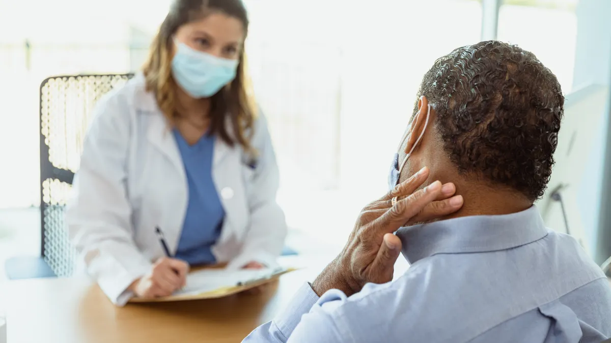 Man discusses neck pain with female physician