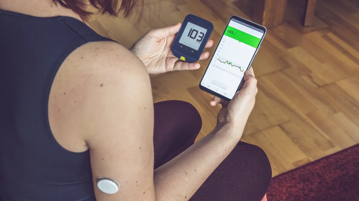 Woman comparing result of glucose level check on the traditional glucometer and on the mobile phone