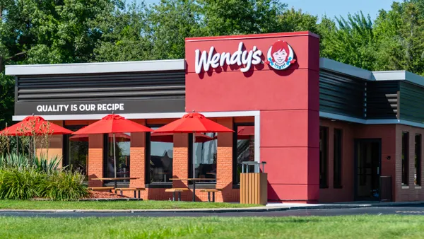 A photograph of a red building with patio umbrellas and a sign that says Wendy's