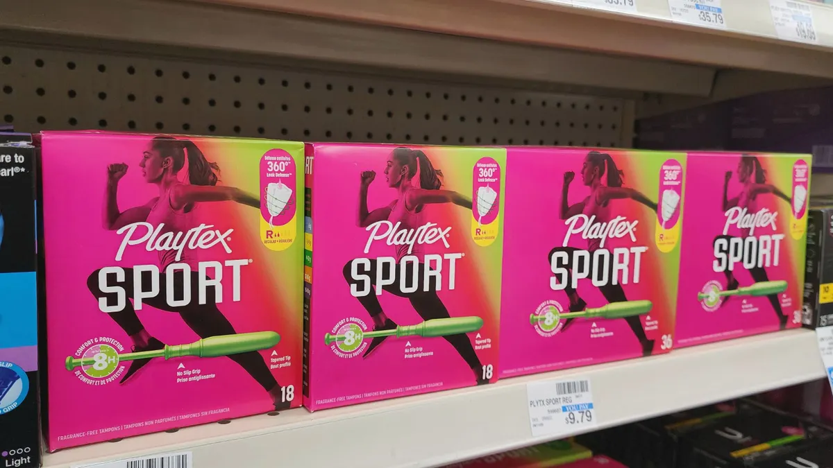 A row of hot pink Playtex Sport tampon boxes on a store shelf.