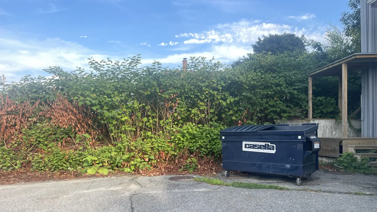 A blue Casella Waste container in the parking lot of an industrial building