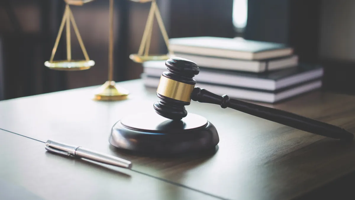 Scales of justice and a gavel lay on a wooden table.