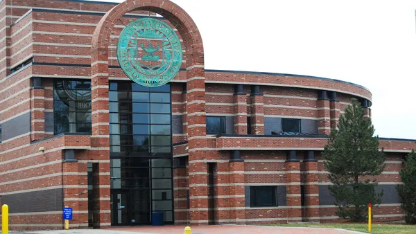 Brick building with green round sign out front.