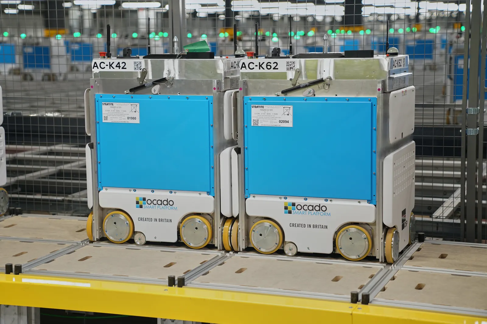 Two blue and gray robotic vehicles in a warehouse.