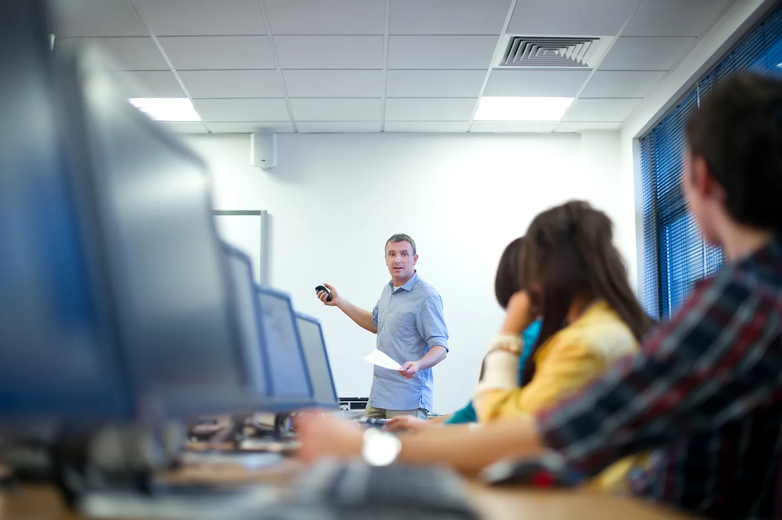 Students sit at computer terminals in a classroom.