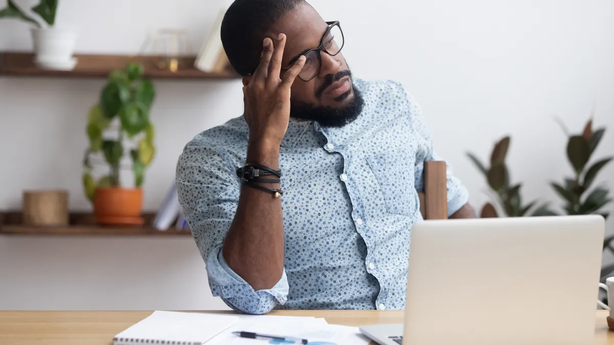 Serious thoughtful african businessman sitting at desk