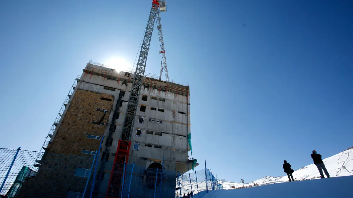 A crane works on a resort on a snow-covered mountainside.