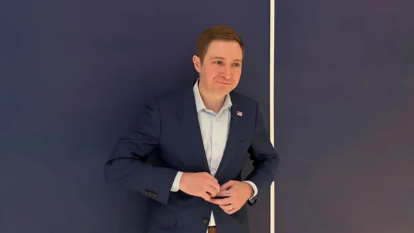 A man in a blue jacket against a blue wall