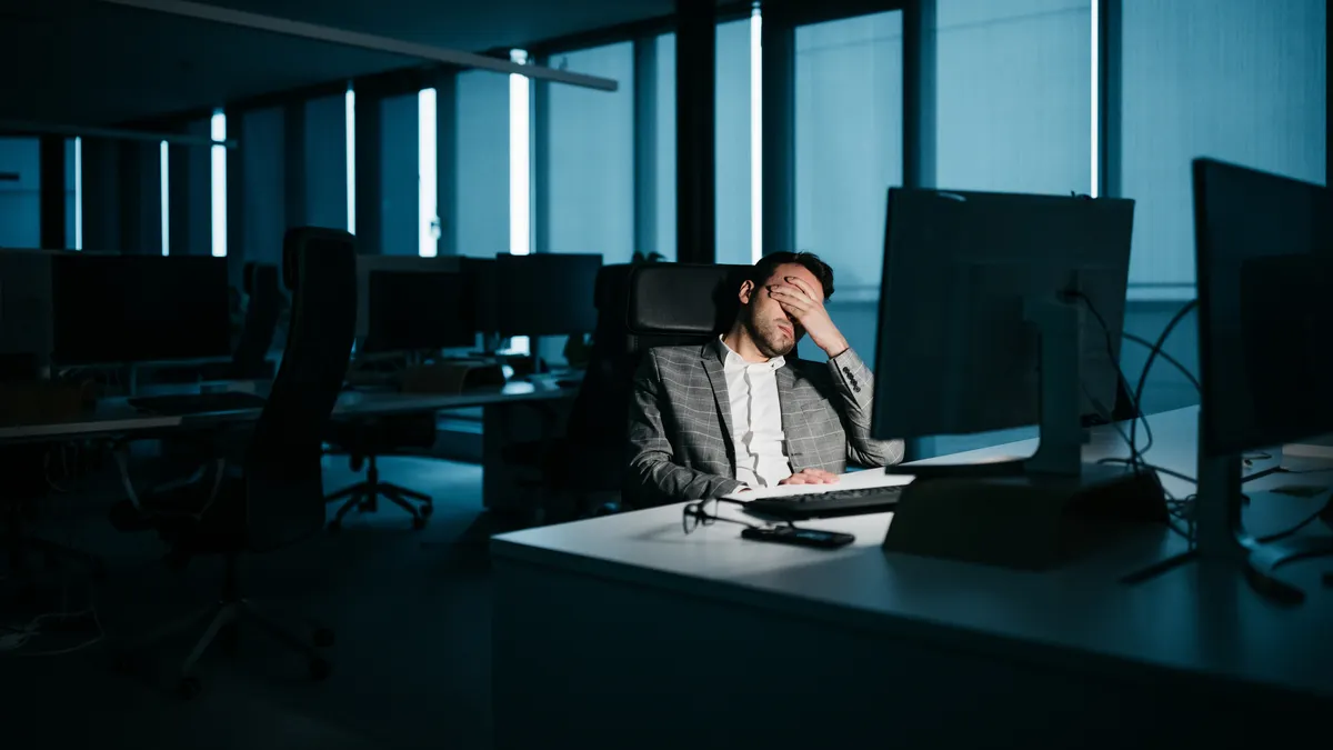 A smartly-dressed businessman is resting in his office in front of his computer.