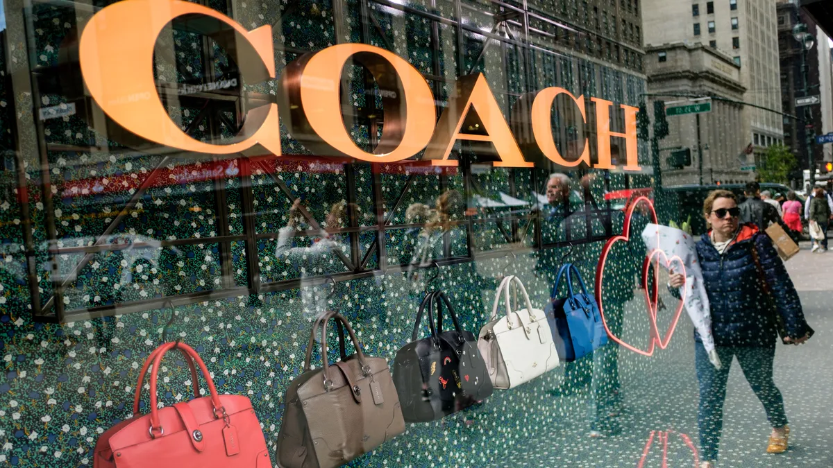 A person walks past a Coach window display.