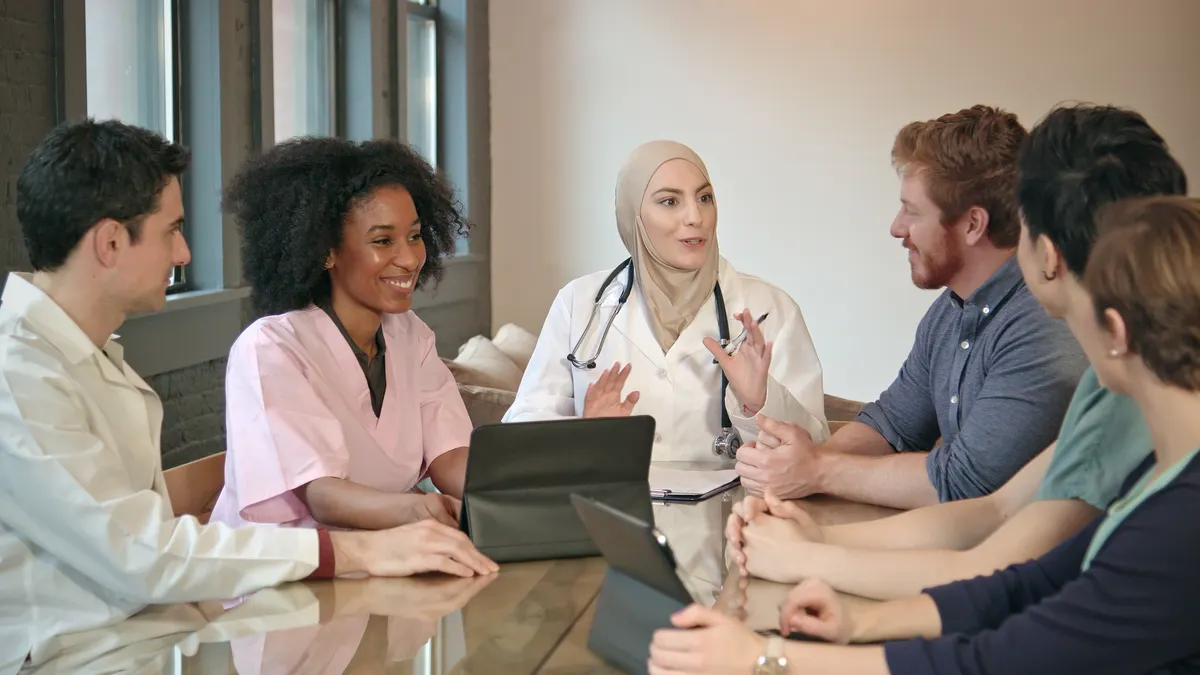Wide shot of a confident Muslim doctor meeting with healthcare professional team.