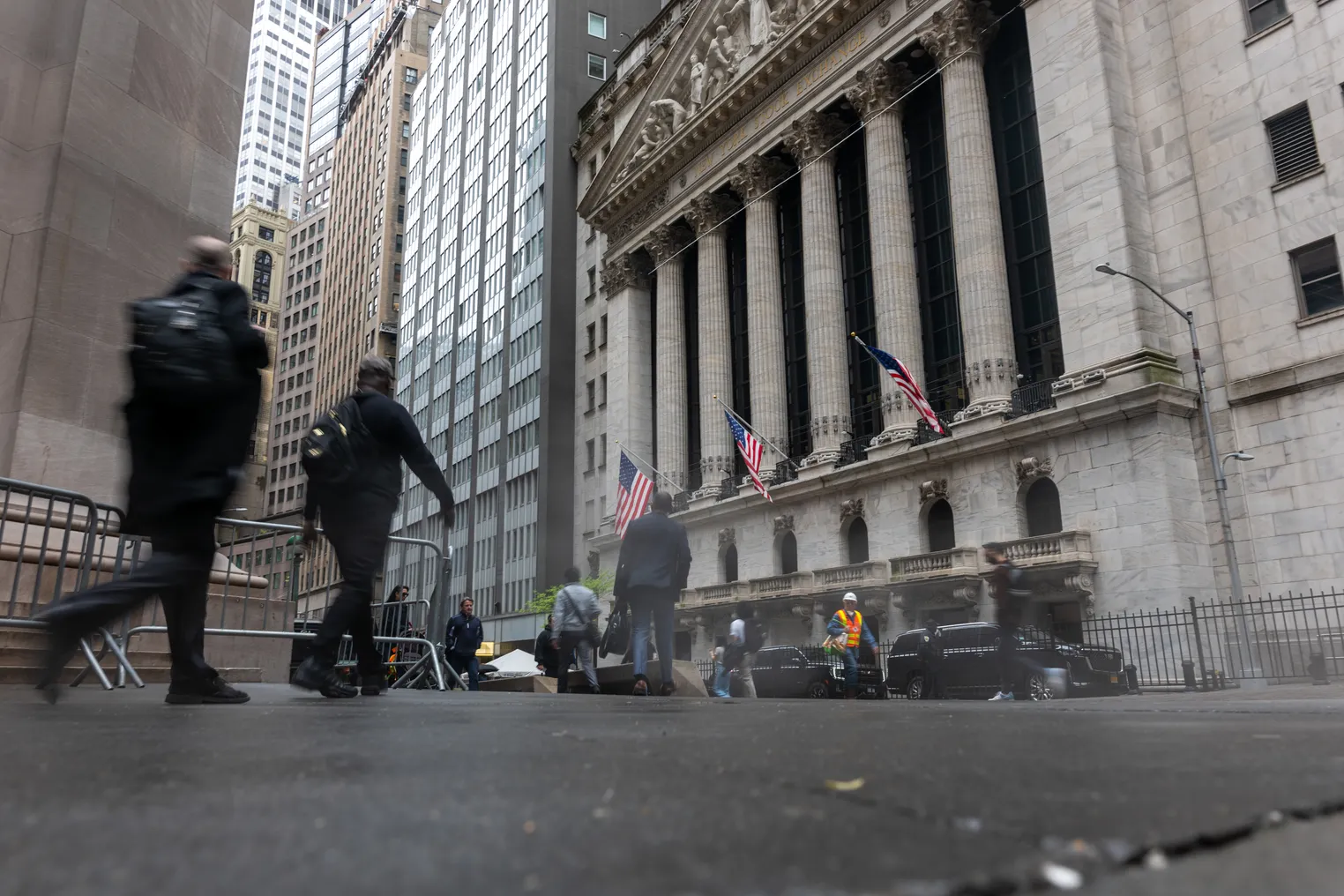 Several people walk by the New York Stock Exchange building