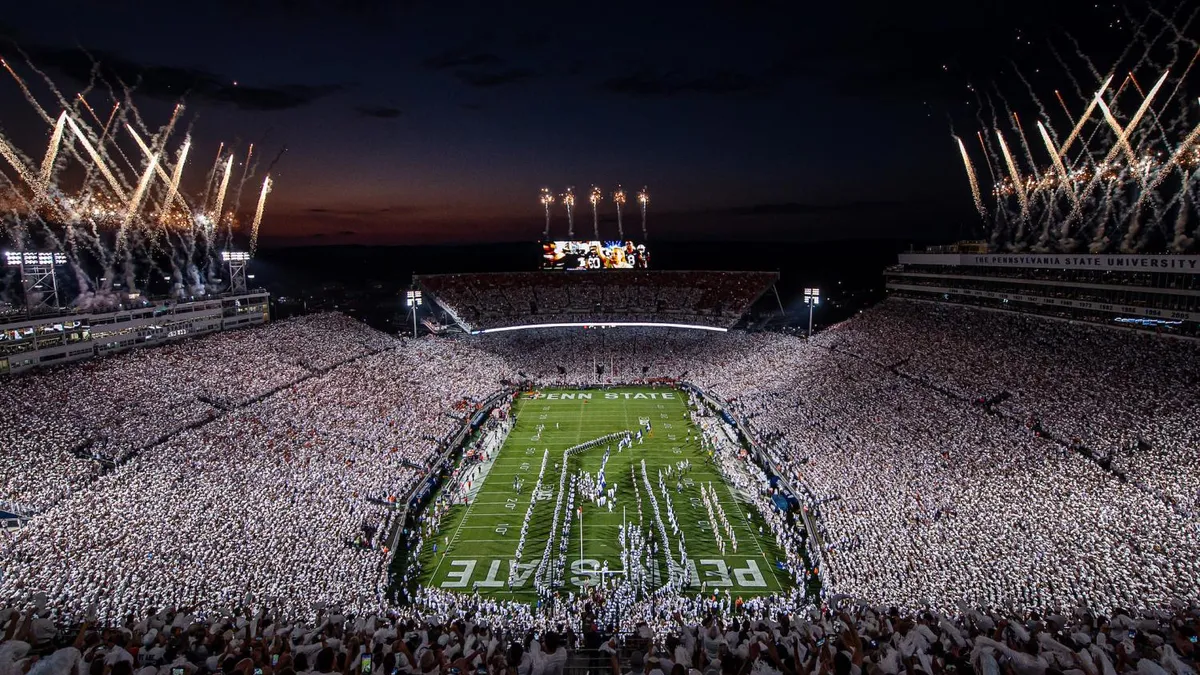 A massive stadium filled with fans watching fireworks.