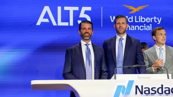 Two men in blue suits standing behind a podium and looking out to the left.