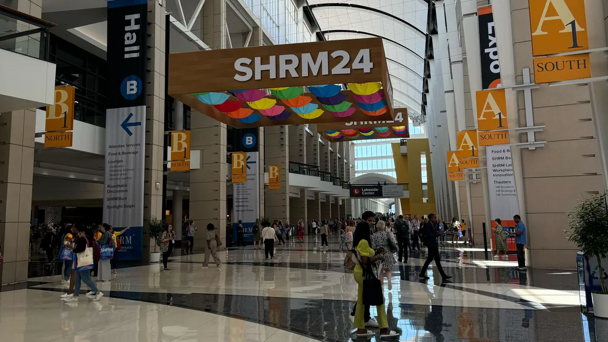 Individuals walk through a conference hall below a SHRM 2024 sign.