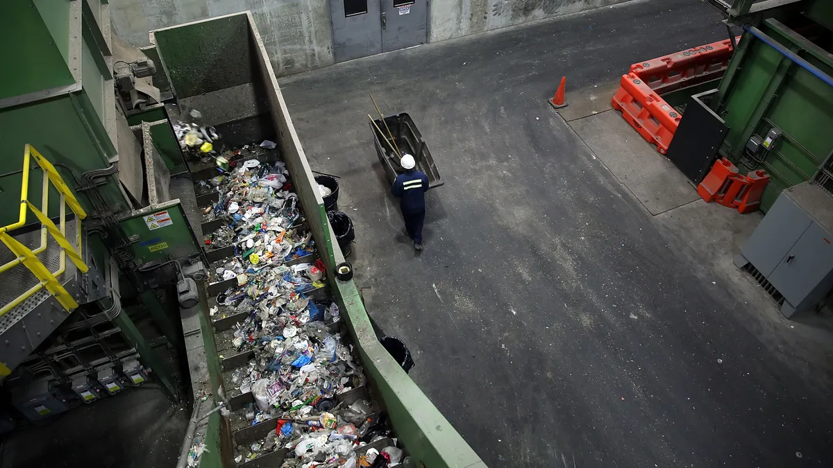 Man pushing a cart in industrial facility, next to machinery with recyclables