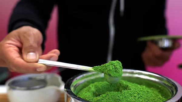 A barista is seen in a close up shot scooping matcha powder