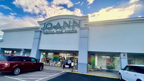 White clouds streak a blue sky above a strip-center retail store.