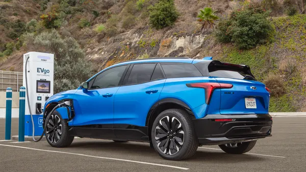 A bright blue 2024 Chevy Blazer EV plugged into a EVgo-branded charger.