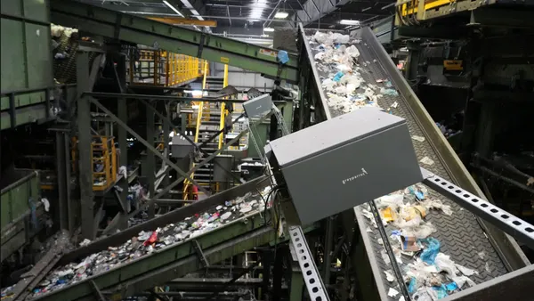 A grey box sits on top of a sorting line with mixed recyclables in a materials recovery facility.
