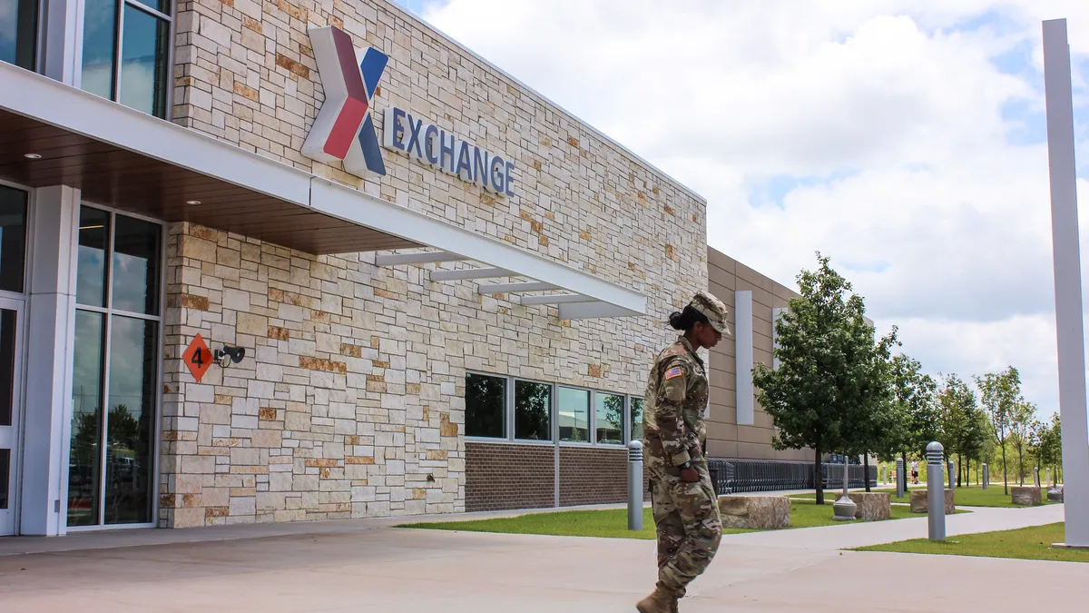 A soldier in combat uniform walks outside an AAFES retail storefront