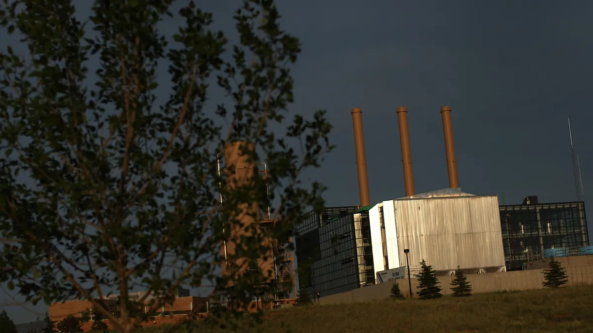 A Wyoming coal-fired power plant is in view partially obscured by a tree in the front left foreground.