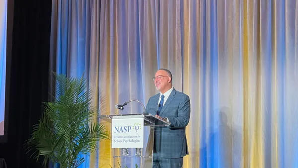 Miguel Cardona stands at a podium that says "NASP" on it.