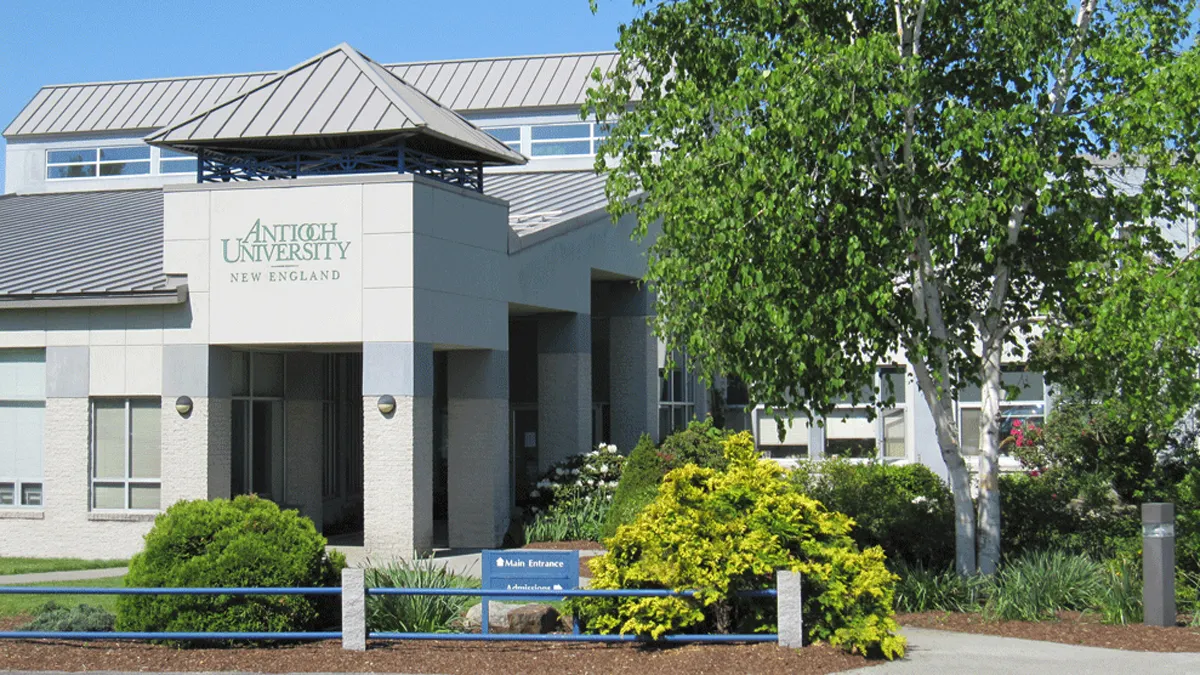 A white modern building with Antioch University banner on turret.