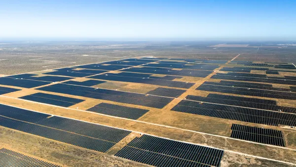 An aerial view of a large solar farm in a desert landscape.
