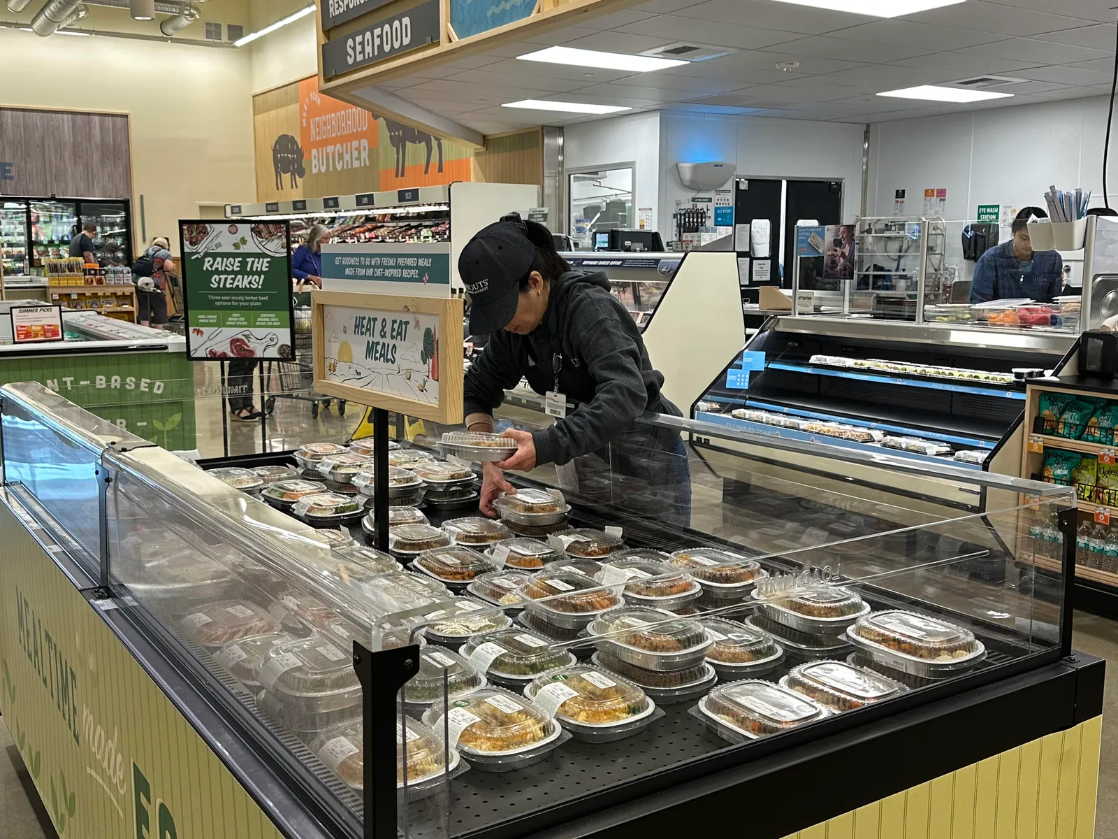 Sprouts employee restocking Heat & Meat meal offerings