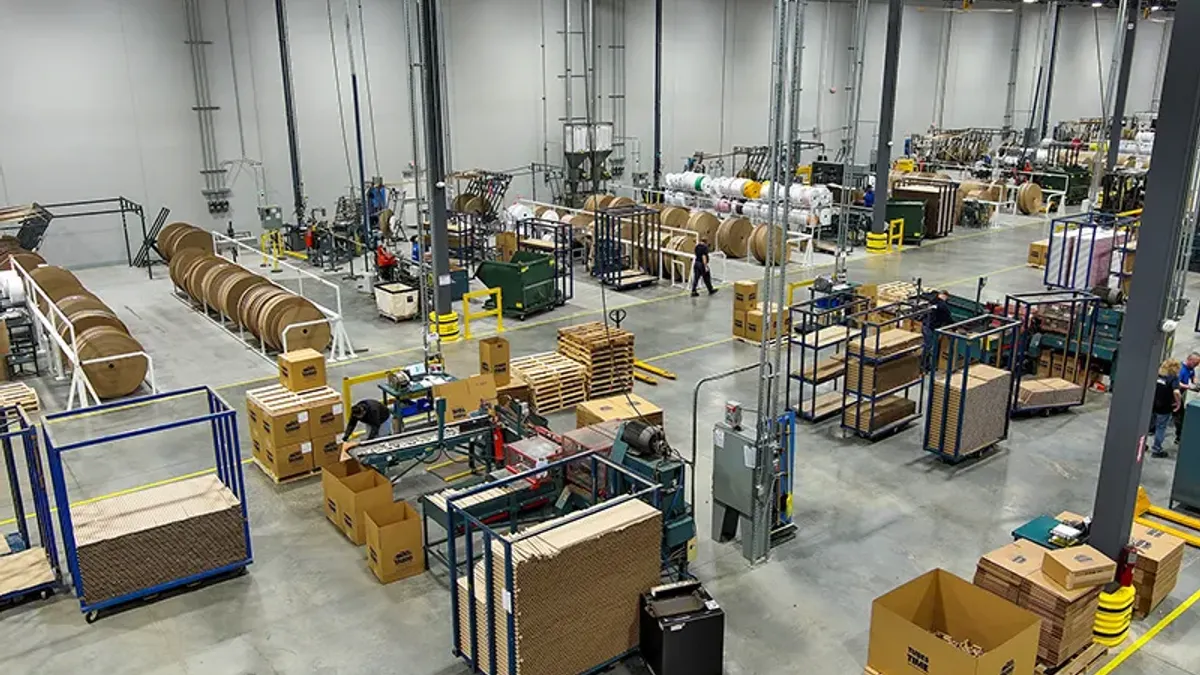 An aerial ivew of an industrial facility's interior shows equipment and fiber packaging on the manufacturing floor.