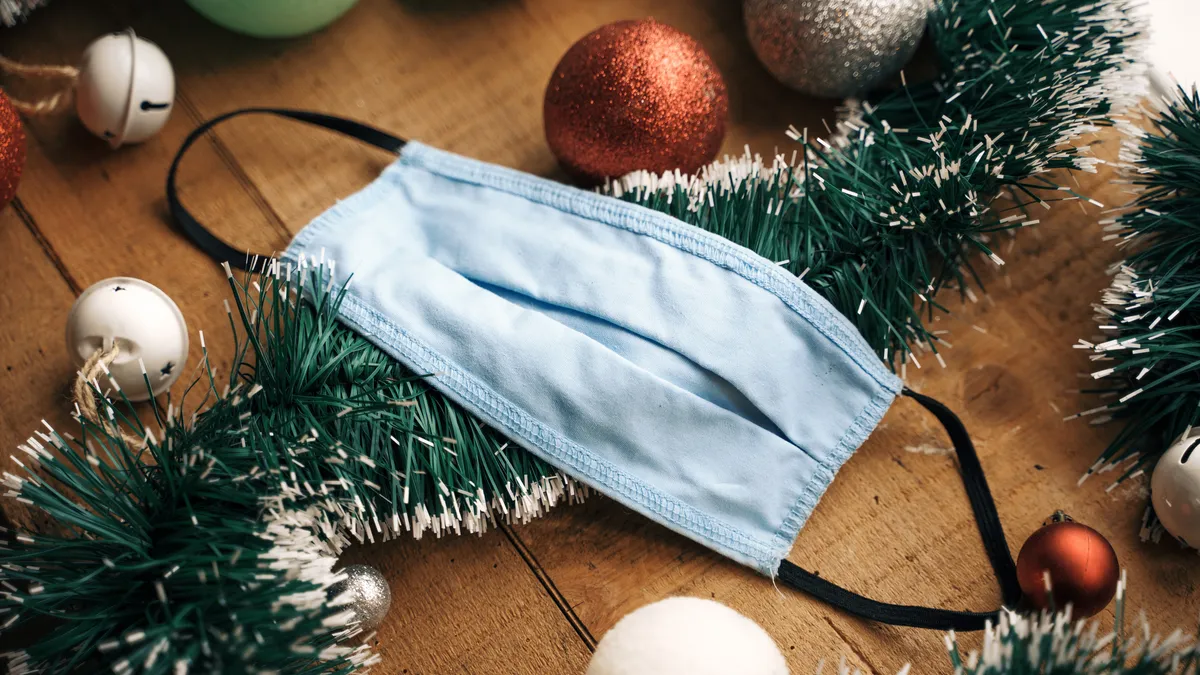 A mask lays over a Christmas garland