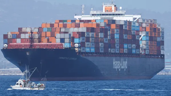 A small fishing boat passes a large container ship near the Port of Los Angeles