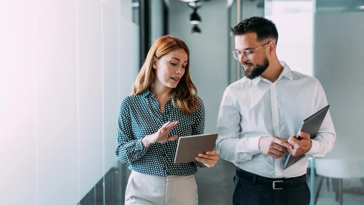Shot of two coworkers having a discussion in modern office.