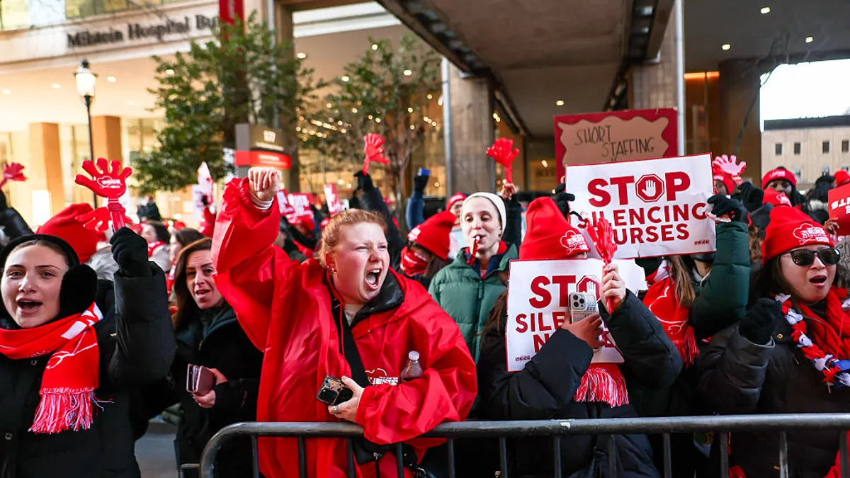 Nurses chant and hold signs saying "Stop silencing nurses" outside of a New York City hospital building.