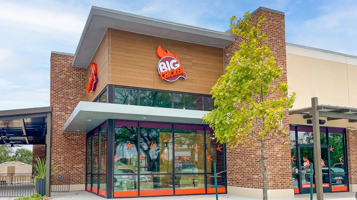 An image of a building with glass front and orange logo that says Big Chicken