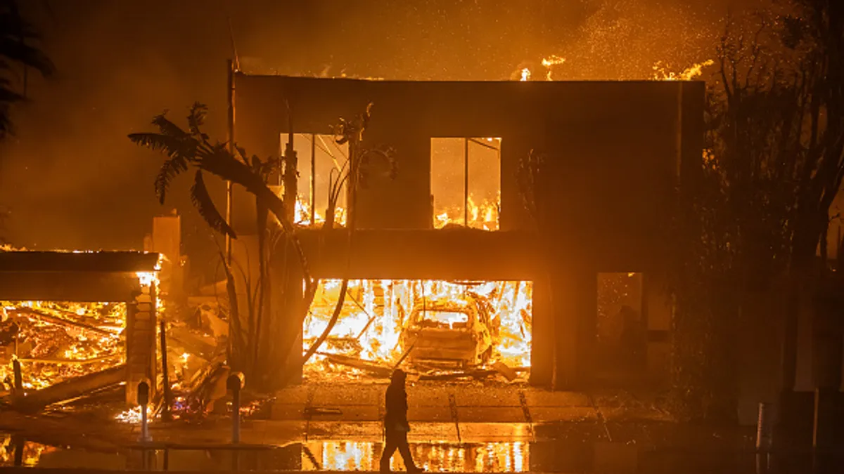 a firefighter stands in front of a burning house