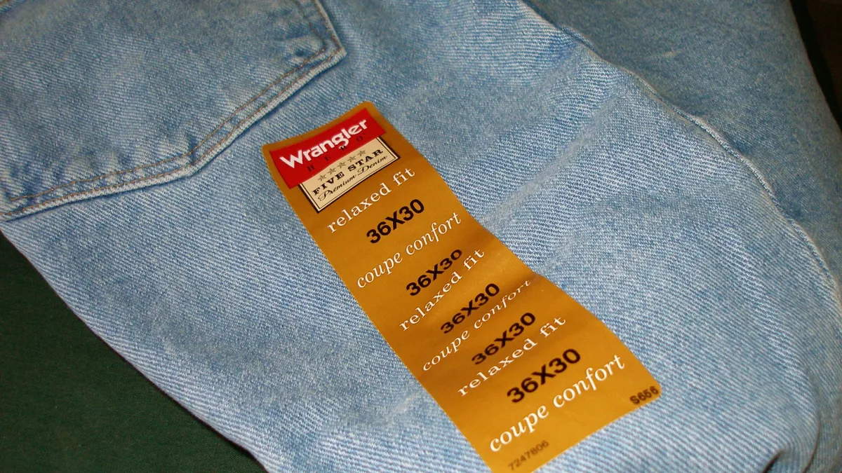 A pair of jeans with their size label are laid out on a blank background.