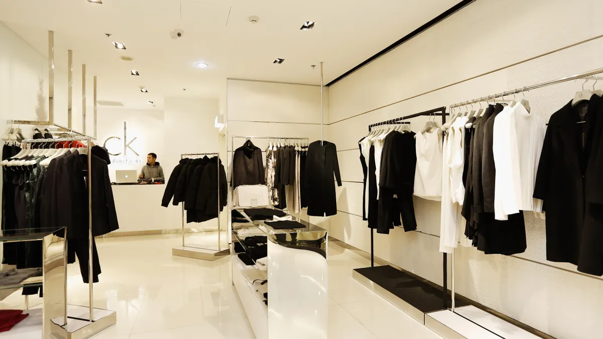 The inside of a Calvin Klein retail store is pictured, showing racks of clothing in primarily neutral colors.