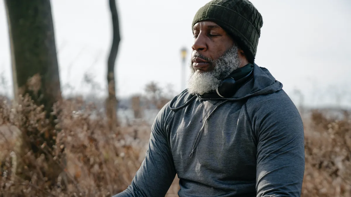 A Black person meditates outside